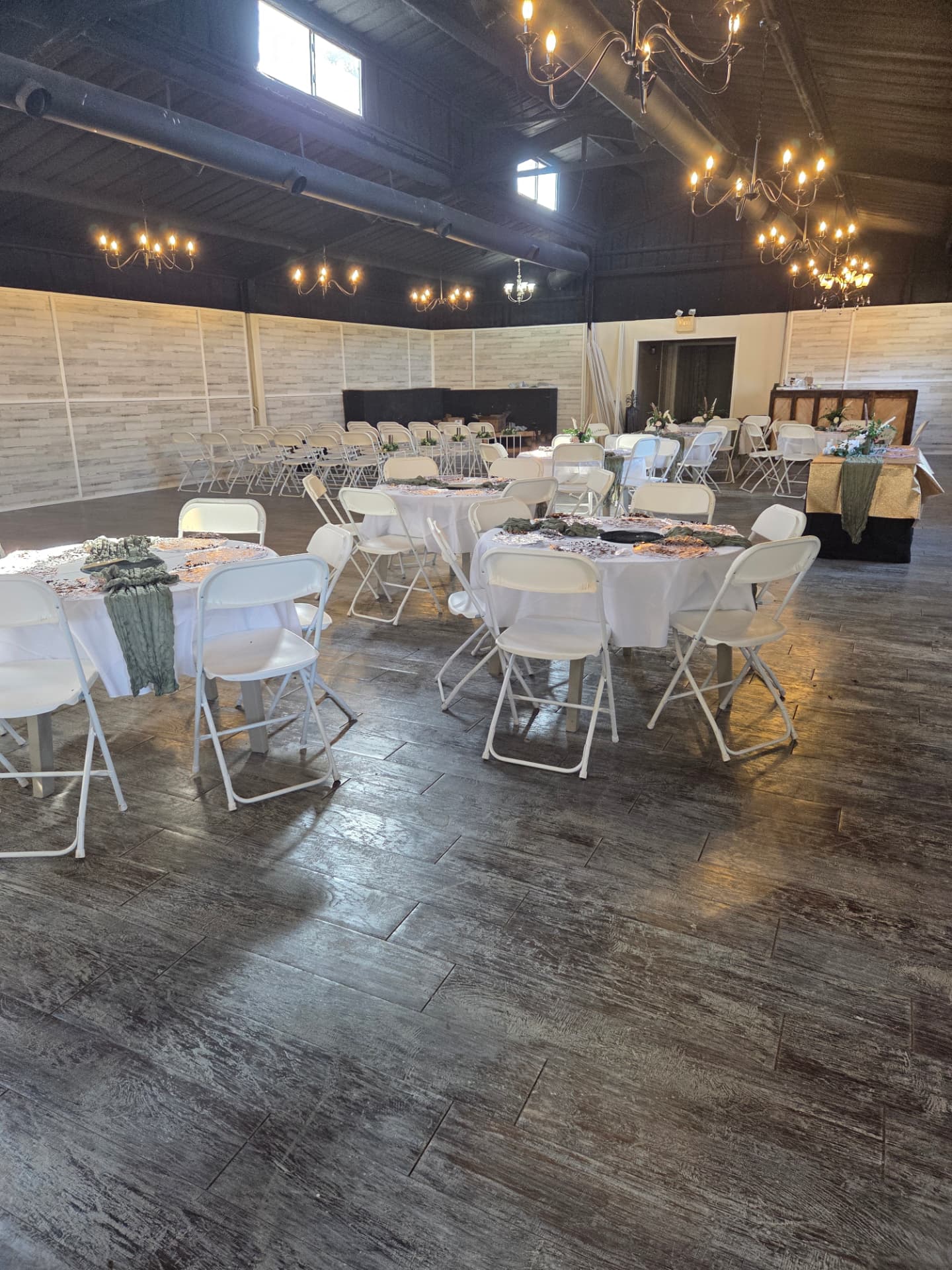 Round guest tables with sage runners beneath warm chandelier light