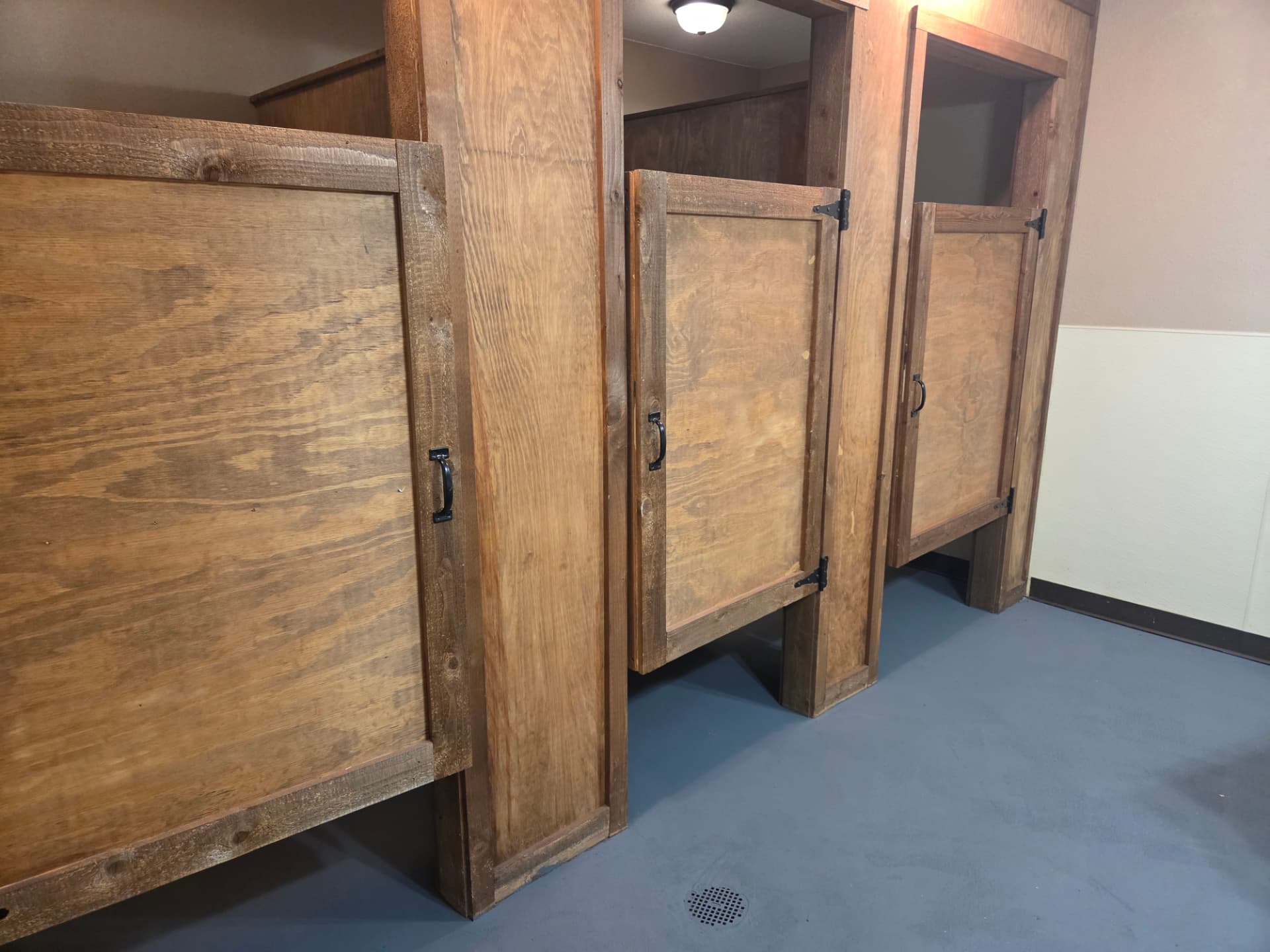 Custom rustic wood restroom stall doors with black iron hardware